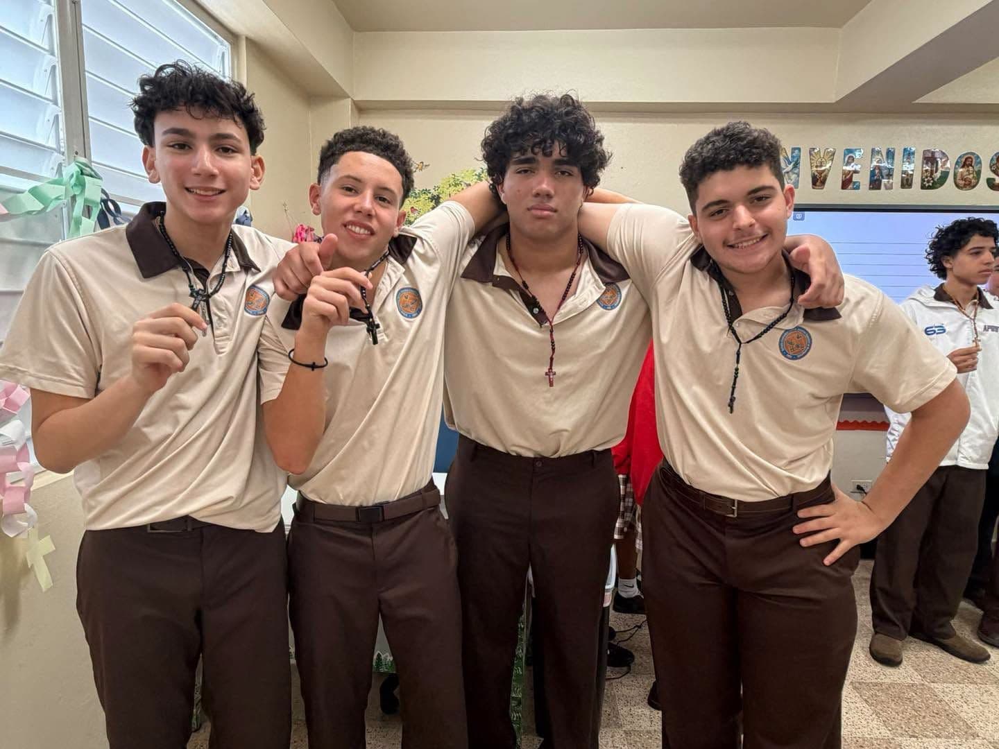 Cuatro estudiantes de secundaria sonríen abrazados en el salón