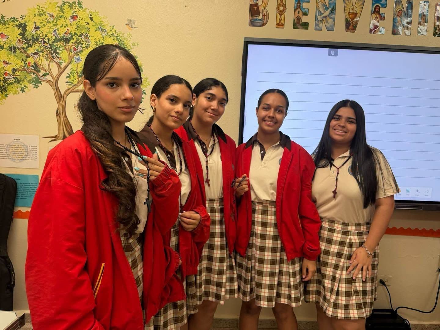 Estudiantes de secundaria con chaquetas rojas del uniforme frente a la pizarra