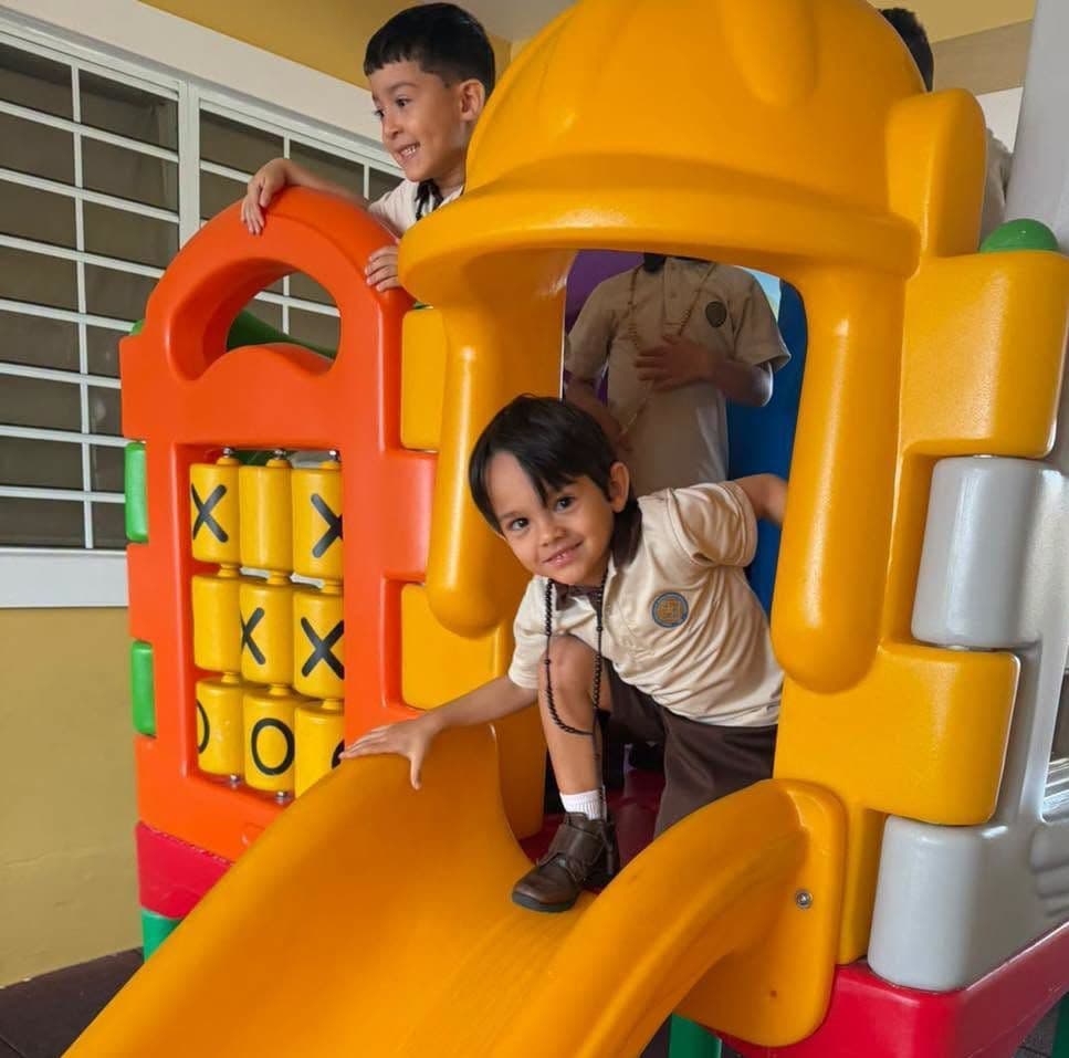 Niños de preescolar juegan en la casita con tobogán del salón