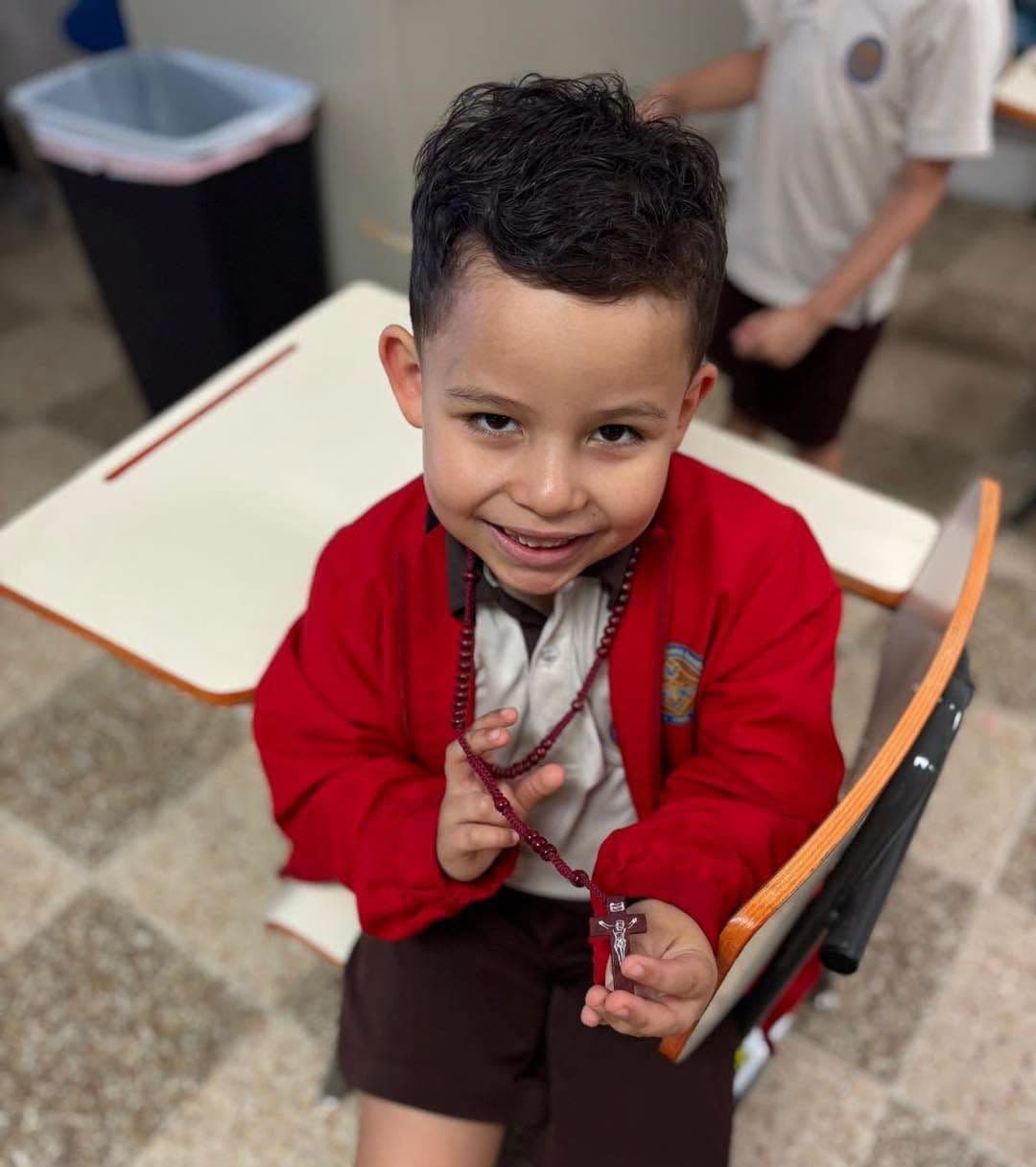 Niño de preescolar sonríe sentado en su pupitre